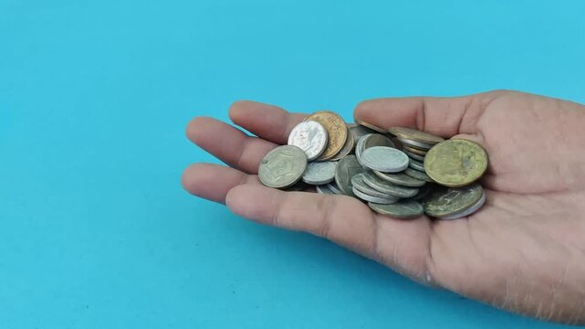 A hand with coins receives more falling ones, symbolizing Zakat requests during Ramadan, light blue background