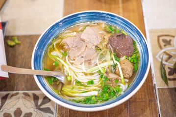 Traditional Hue noodle “Bun Bo Hue” with pig blood cubes, beef slices, rich spicy soup deep...