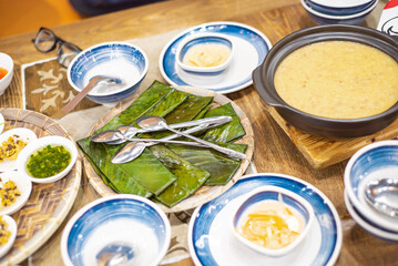 Flat chewy tapioca dumpling banana leaves wraps with large bowl rice soup, small dishes, dipping sauce, bamboo mat, traditional Hue dinner set, authentic Vietnamese cuisine balanced eating