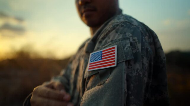 Us Army veteran honors Veterans Day. Man soldier adjusts the US military patch before duty. A US soldier with an American flag patch on his uniform prayers for Memorial Day. Independence Day.
