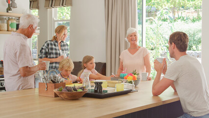 Multi-Generation Family At Home Standing Around Table With Hot Drinks Together