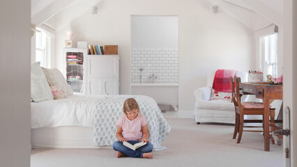 Young Girl Sitting On Floor In Cool Bedroom Reading Book