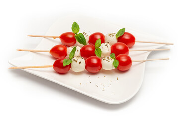 Caprese skewers with tomatoes on a plate on a white background