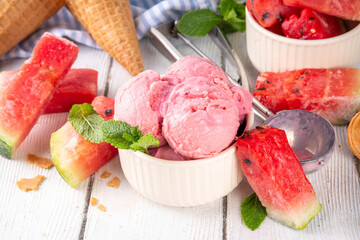 Homemade watermelon ice cream, sweet red melon sorbet gelato in portioned bowl, with watermelon slices and mint on white wooden table background