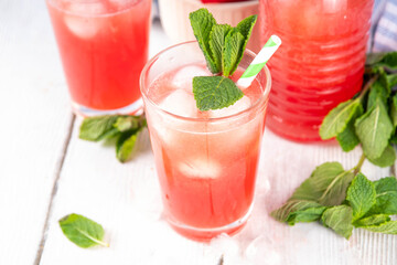 Homemade watermelon lemonade, sweet refreshing summer drink, iced watermelon juice with mint decor and striped straw, light blue and wooden background, copy space 