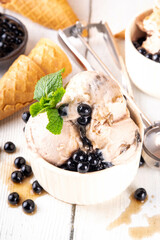 Bubble milk tea ice cream, sweet taiwanese asian style milky tea with Kuromitsu, black boba or tapioca pearls and syrup, in portioned bowls with ice cream cones, white wooden table copy space