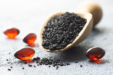 Pills of black cumin seeds essential oil on rustic background. Nigella Sativa capsules, healthy food supplement