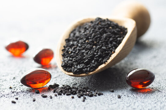 Pills of black cumin seeds essential oil on rustic background. Nigella Sativa capsules, healthy food supplement