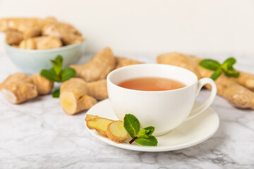Cup of hot ginger tea with slices of ginger root on wooden background. Warming drink. Alternative medicine. Tea with honey, lemon, ginger and mint. Space for text. Copy space