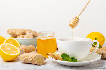 Cup of hot ginger tea with slices of ginger root on wooden background. Warming drink. Alternative medicine. Tea with honey, lemon, ginger and mint. Space for text. Copy space