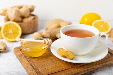 Cup of hot ginger tea with slices of ginger root on wooden background. Warming drink. Alternative medicine. Tea with honey, lemon, ginger and mint. Space for text. Copy space