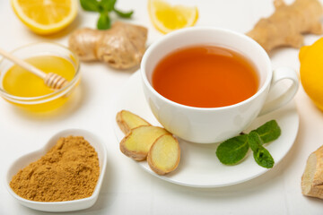 Cup of hot ginger tea with slices of ginger root on wooden background. Warming drink. Alternative medicine. Tea with honey, lemon, ginger and mint. Space for text. Copy space