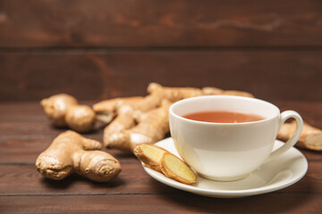 Cup of hot ginger tea with slices of ginger root on wooden background. Warming drink. Alternative medicine. Tea with honey, lemon, ginger and mint. Space for text. Copy space