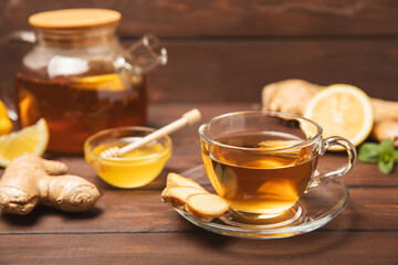 Cup of hot ginger tea with slices of ginger root on wooden background. Warming drink. Alternative...