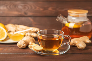 Cup of hot ginger tea with slices of ginger root on wooden background. Warming drink. Alternative medicine. Tea with honey, lemon, ginger and mint. Space for text. Copy space