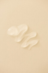 Clear transparent skincare gel or lubricant on beige minimal background. Cleanser, serum, shampoo beauty product wavy smear