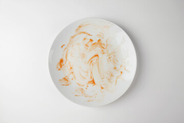 Dirty plate isolated, empty bowl after dinner, ready lunch, smeared ketchup sauce on white plate background.