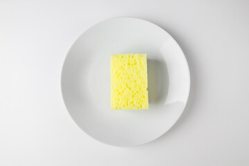 White plate with sponge for cleaning dishes on white background.