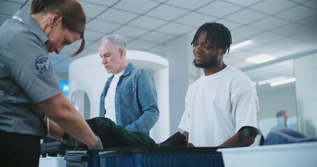 Airport Security Checkpoint: Female Security Officer Checking Suitcase of Traveler before Boarding...