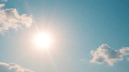 Bright sun shining in a clear blue sky with scattered clouds, conveying warmth, clarity, and a sense of open space