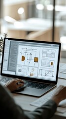 A person works on a laptop, designing wireframes and layouts for digital projects in a bright, modern office space