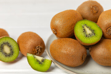 Kiwi on wooden background. Whole fruit and slices pieces of green kiwi on table. fresh ripe juicy kiwi. Tropical fruit. Organic fruit. Healthy eating. Space for text. Copy space.
