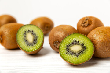 Fototapeta premium Kiwi on wooden background. Whole fruit and slices pieces of green kiwi on table. fresh ripe juicy kiwi. Tropical fruit. Organic fruit. Healthy eating. Space for text. Copy space.