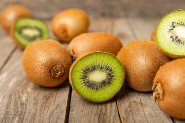 Kiwi on wooden background. Whole fruit and slices pieces of green kiwi on table. fresh ripe juicy...