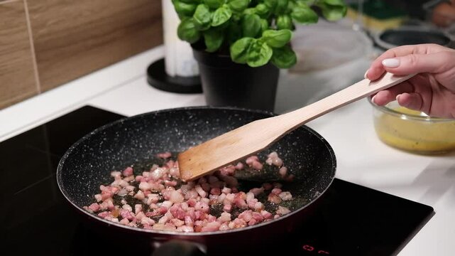 chef roasts cubes of bacon or Italian pork guanciale or pancetta in a pan for Italian pasta carbonara , A woman cooking Italian spaghetti carbonara pasta 