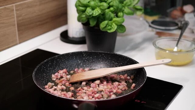 chef roasts cubes of bacon or Italian pork guanciale or pancetta in a pan for Italian pasta carbonara , A woman cooking Italian spaghetti carbonara pasta 
