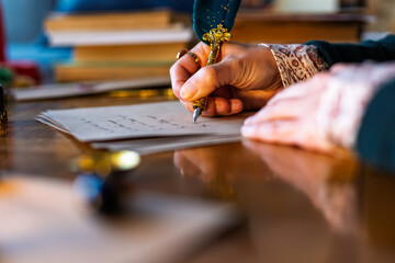 Close up of girl's hand writing calligraphy with ink pen. Professional calligrapher writing a...