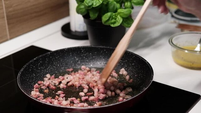 chef roasts cubes of bacon or Italian pork guanciale or pancetta in a pan for Italian pasta carbonara , A woman cooking Italian spaghetti carbonara pasta 