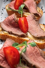 Bruschetta with meat, cherry tomatoes and cheese