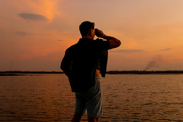 Man using binoculars to view the sunset.
