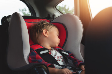 Adorable boy peacefully sleeping in  a car seat inside a vehicle