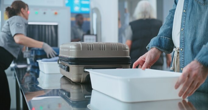 Security Checkpoint in Airport: Diverse People, Tourists Putting Personal Items and Baggage for X-ray Scanning, Then Walking Through Metal Detector Scanner. TSA Worker Controlling Screening Procedure.