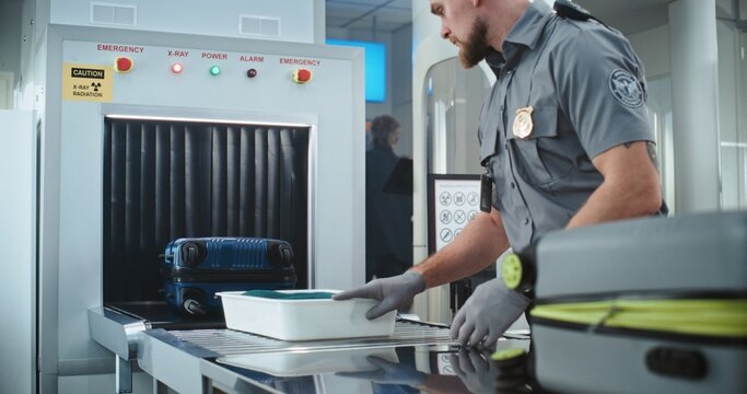Airport Security Checkpoint: Security Officer Putting Suitcases and Personal Items in Trays on Conveyor Belt with X-ray Scanning. People Passing Through Metal Detector Gates. TSA Screening Procedures.