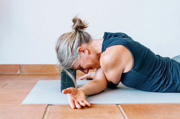 Woman practicing yin yoga crossed arm stretch, head supported by block