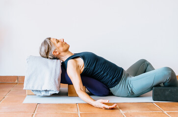 Woman practicing supported restorative yoga with props