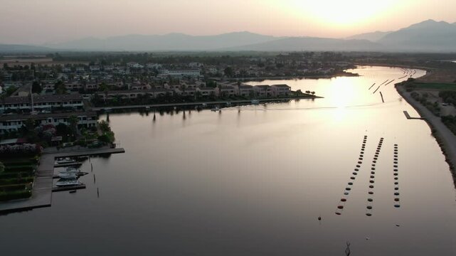 A drone over a small town on a lake. Marinas, Cloudy summer sunset. Sibari, Italy.