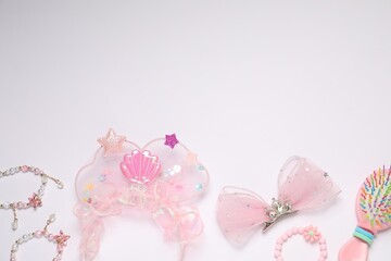 Different hair accessories and brush on light background, flat lay. Space for text