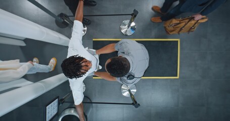 Security Checkpoint, TSA Screening Procedures: Diverse People Passing Through X-ray Metal Detector Scanner, African American Airport Worker Checking Passengers. Crowd of Travelers in Airport. Top View