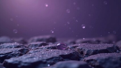A single, glistening droplet rests on a rough, textured surface, surrounded by a gentle rain of smaller droplets against a soft purple backdrop.