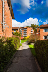Charming residential pathway in Sweden surrounded by greenery and apartments on a sunny day