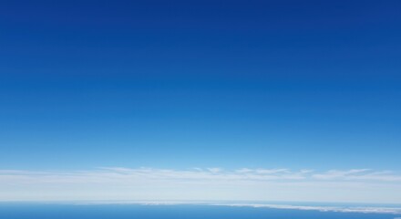 Fototapeta premium Clear blue sky over the ocean with wispy clouds on the horizon, serene view