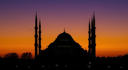 Obraz premium Silhouette of a grand mosque at sunset with vibrant orange and purple sky