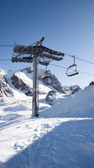 Ski cable-way high in the mountains with snowy rocks, blue sky and fresh air.