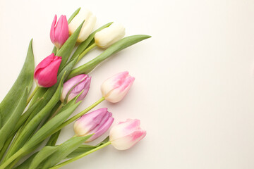 hello spring text sign, beautiful pink tulips on white rustic wooden background flat lay. flowers in soft morning sunlight with space for text. greeting card concept