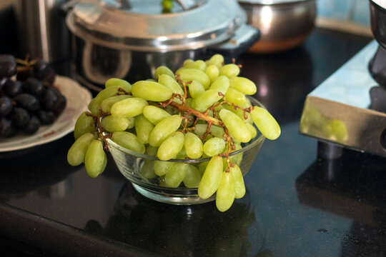 Fresh and green Grapes bunch in glass bowl on kitchen black stone platform