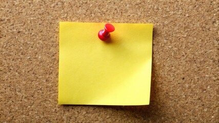 A pinned yellow sticky note on a brown cork bulletin board offers a blank space for an office memo